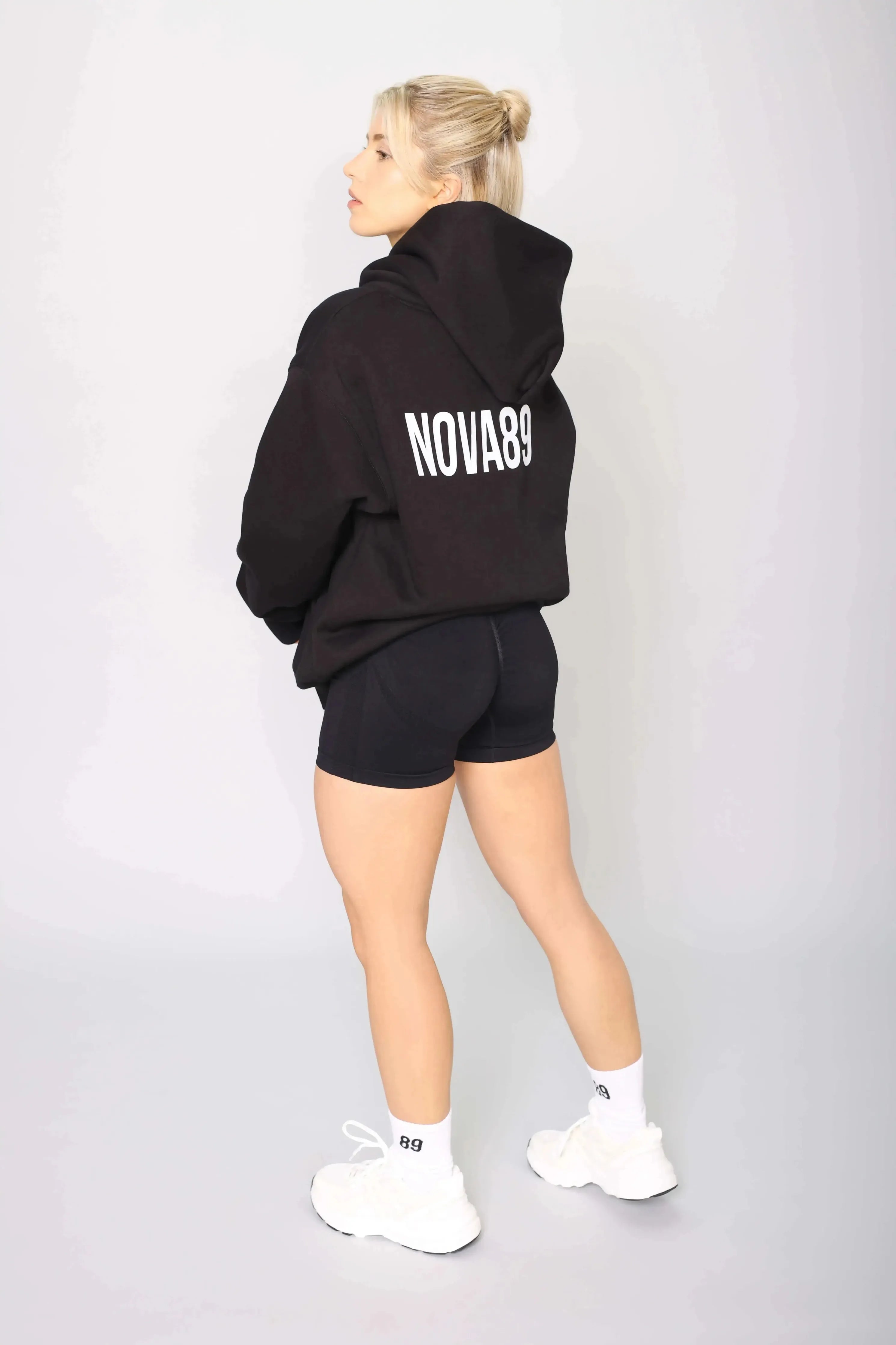 Back view of a women’s black pullover gym hoodie with an oversized fit